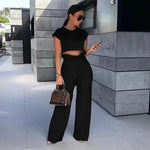 a woman in a crop top and wide legged pants looking at her cell phone