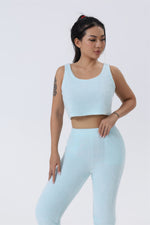 a woman in a light blue crop top and leggings