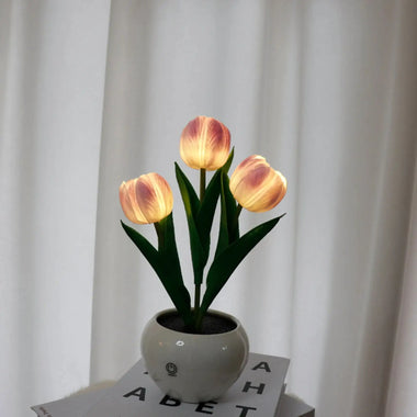 a white vase with three yellow tulips in it