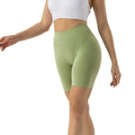 a woman in a white top and green shorts