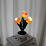 three orange tulips in a white vase on top of a stack of books