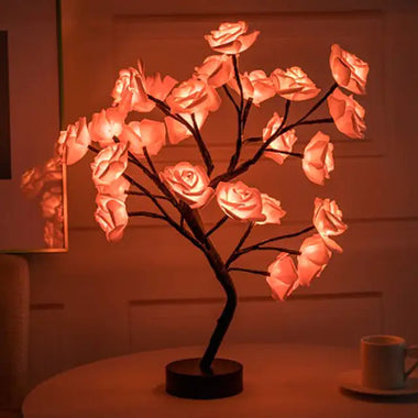 a table with a lamp that has a tree with roses on it