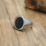 a silver and black signet ring on a wooden table