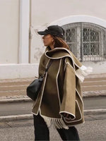 a woman walking down the street wearing a cape