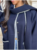 a woman wearing a blue coat with white trims