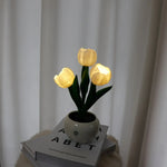 a white vase filled with yellow flowers sitting on top of a pile of books