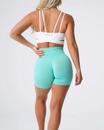 a woman in mint green shorts and a white bra top