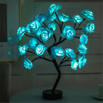 a lighted tree with blue roses on a table