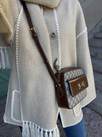 a woman wearing a white coat and a brown purse