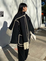 a woman walking down a sidewalk wearing a black coat