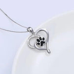 a heart shaped pendant with a dog's paw inside of it