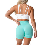 a woman in mint green shorts and a white bra top