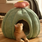 a cat is looking up at a stuffed pumpkin