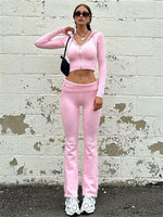 a woman in a pink outfit standing in front of a white brick wall