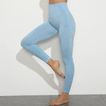 a woman in blue leggings leaning against a wall