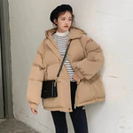 a woman standing against a wall wearing a coat and hat