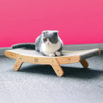 a gray and white cat sitting on a wooden cat bed