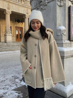 a woman wearing a coat and a hat standing in the snow