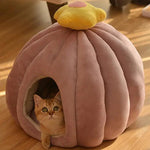 a cat sitting inside of a pink ball shaped bed