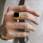 a man wearing a gold ring with a black stone